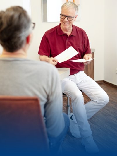 Ein Arzt spricht mit seinem Patienten in einem Praxisoutfit von BP®.